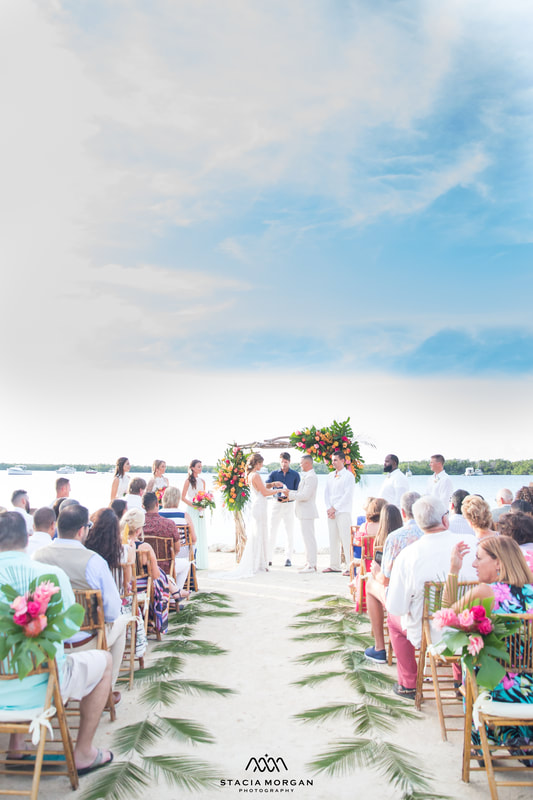 South Florida wedding, bright flowers on arch and green palms along aisle